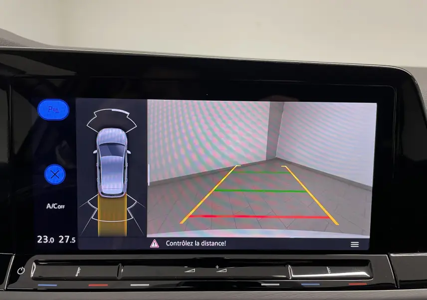 Écran multimédia affichant la caméra de recul et l’aide au stationnement de la Volkswagen Golf blanche vue de dessus.