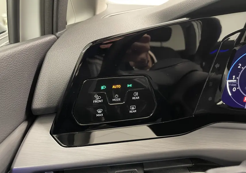 Panneau de commandes d'éclairage et désembuage à gauche du tableau de bord d'une Volkswagen Golf blanche 2023.