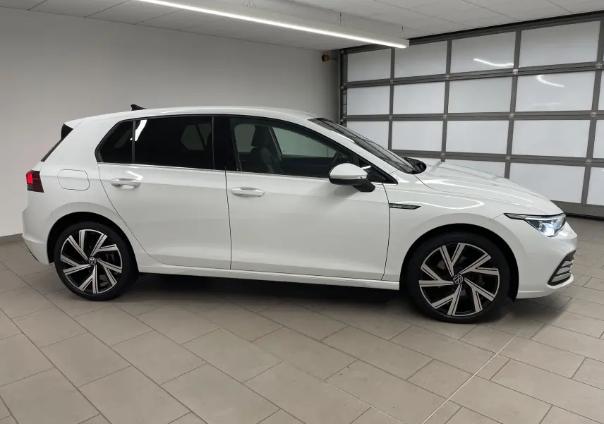 Volkswagen Golf 1.5 eTSI 2023 blanc pur vue de profil côté gauche avec jantes alliage Bergamo et vitres arrière surteintées.
