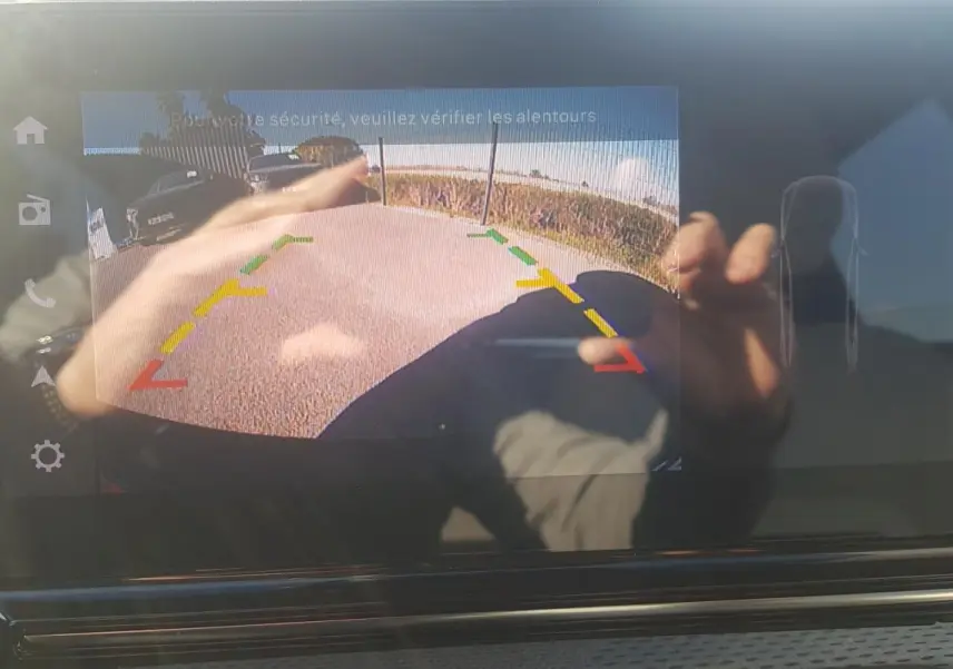 Écran de caméra de recul de la Citroën C3 bleu foncé 2024 avec guidage coloré et reflets de mains.