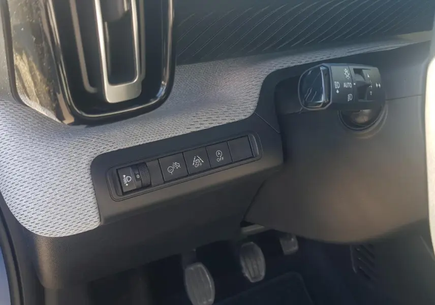 Détail intérieur côté gauche du tableau de bord bleu foncé de la Citroën C3 2024 avec commandes d’éclairage et pédales.