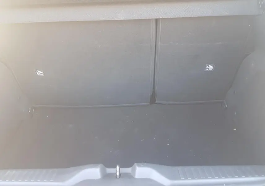 Vue intérieure du coffre vide d'une Citroën C3 2024 bleu foncé, montrant le revêtement noir et les fixations ISOFIX.