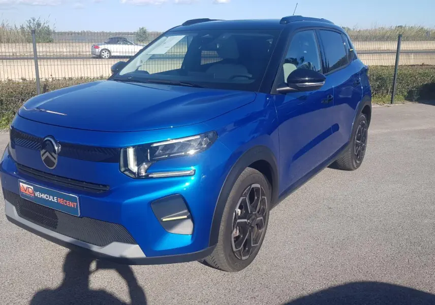 Citroën C3 bleu foncé vue 3/4 avant droit avec barres de toit et jantes alliage noires.