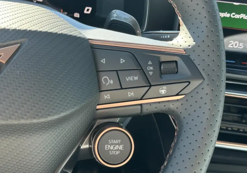 Gros plan sur le volant perforé noir avec commandes et bouton Start Engine Stop du CUPRA Leon Sportstourer gris magnétique.