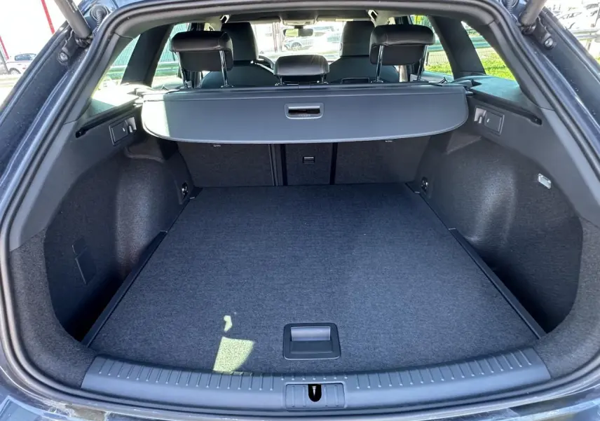 Coffre ouvert vu de l'arrière d'une CUPRA Leon Sportstourer gris magnétique, avec cache-bagages déployé.