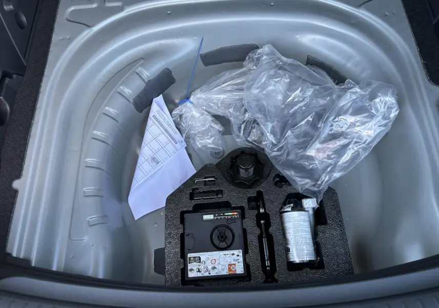 Gros plan sur le coffre ouvert d'une CUPRA Leon Sportstourer gris magnétique, montrant la roue de secours et les outils rangés.