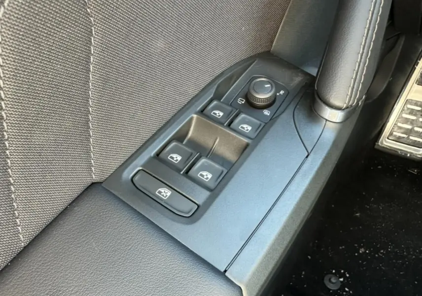 Gros plan sur les commandes de lève-vitres et rétroviseurs côté conducteur du CUPRA Leon Sportstourer gris magnétique 2025.