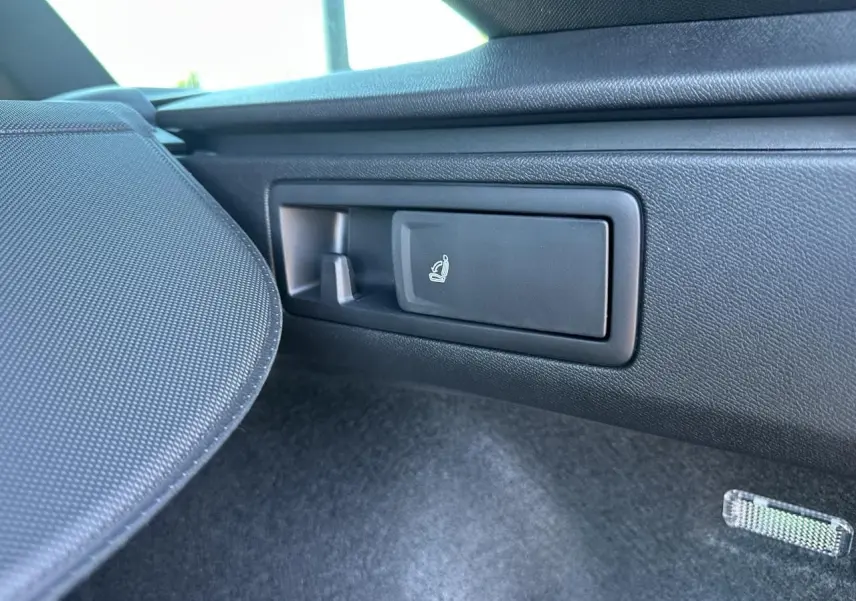 Gros plan sur la commande de rabattement des sièges arrière dans le coffre du CUPRA Leon gris magnétique 2025.
