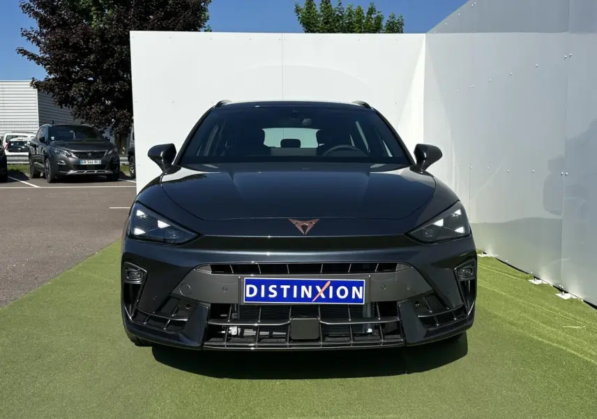 Vue frontale d'une CUPRA Leon Sportstourer gris magnétique avec logo CUPRA cuivré et calandre sportive noire.