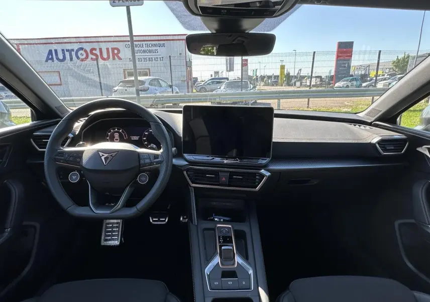 Vue intérieure frontale du poste de conduite noir du CUPRA Leon Sportstourer 2025 avec écran tactile central et volant Supersports.