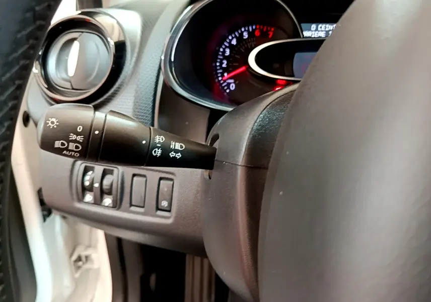 Gros plan sur le commodo gauche et le tableau de bord éclairé d'une Renault Clio Business blanche de 2019.