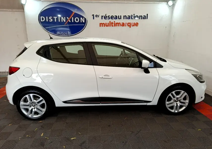 Profil côté gauche d'une Renault Clio Business TCe 90 blanche, avec jantes alliage et poignées de porte ton carrosserie.