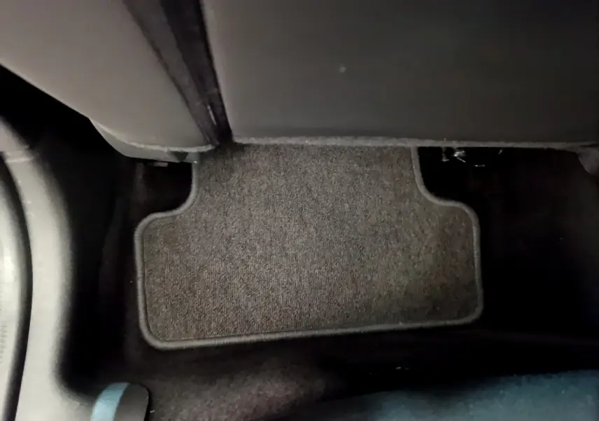 Tapis de sol noir au pied du siège arrière droit d'une Renault Clio Business TCe 90 blanche, vue intérieure rapprochée.