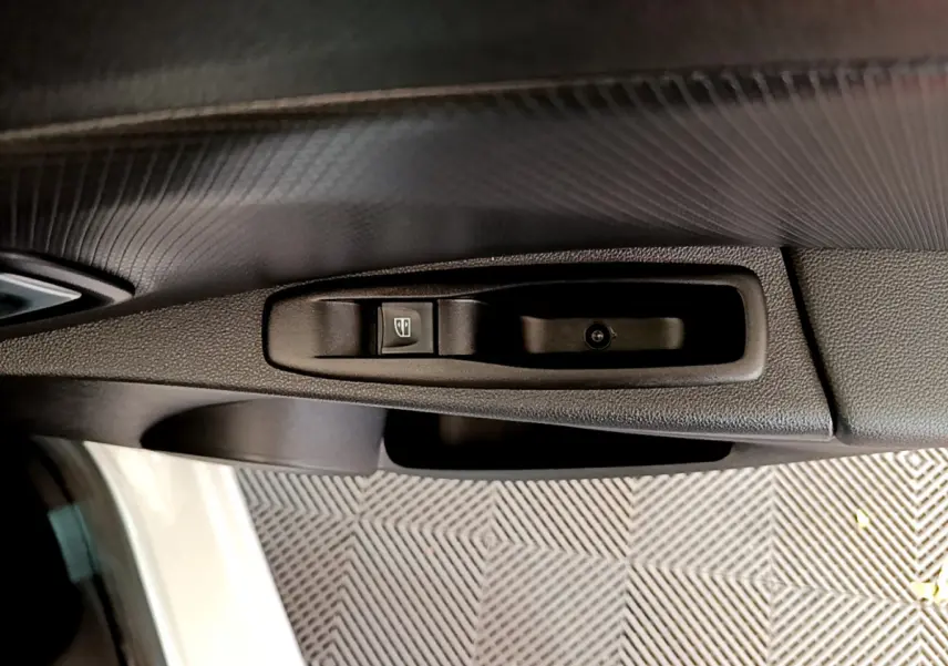 Gros plan sur la commande de lève-vitre côté conducteur d'une Renault Clio Business TCe 90 blanche de 2019.