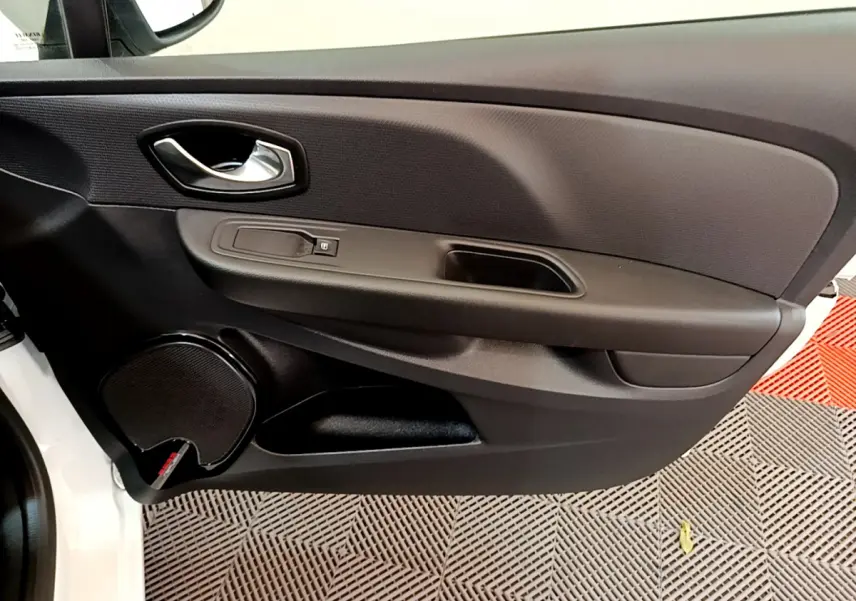 Vue rapprochée de la porte avant gauche noire de la Renault Clio Business TCe 90 blanche, avec poignée et haut-parleur intégrés.