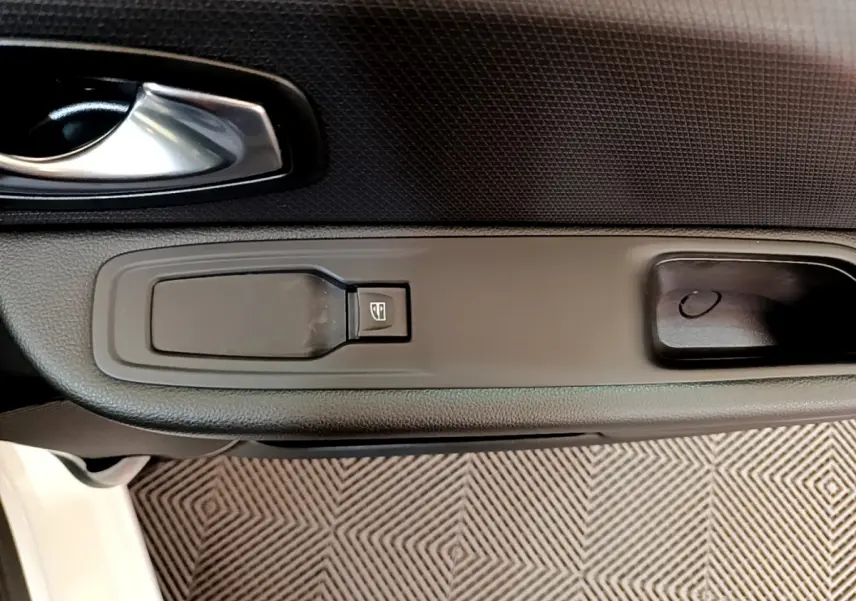 Gros plan sur la poignée intérieure et le bouton de lève-vitre côté conducteur d'une Renault Clio blanche 2019.