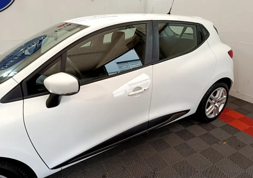 Profil côté gauche d'une Renault Clio Business TCe 90 blanche, avec rétroviseur et poignées assortis visibles.