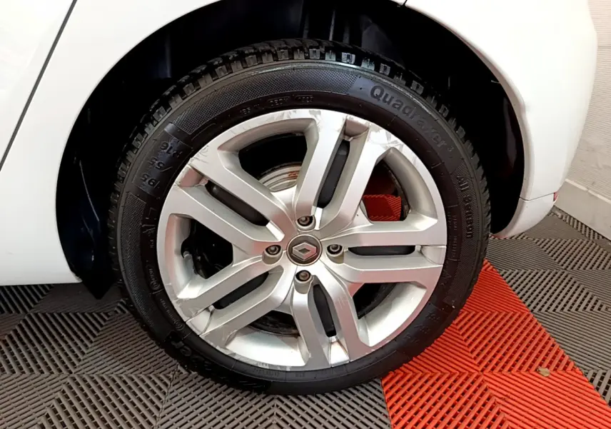 Gros plan sur la roue arrière droite blanche d'une Renault Clio Business TCe 90 avec jante alliage argentée.