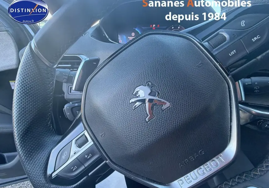 Gros plan sur le volant cuir perforé du Peugeot 3008 bleu 2023 avec logo lion et commandes intégrées.