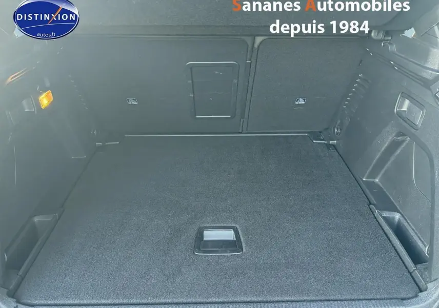 Vue plongeante sur le coffre spacieux et plat du Peugeot 3008 2023, finition GT, avec banquette rabattue et tapis noir.