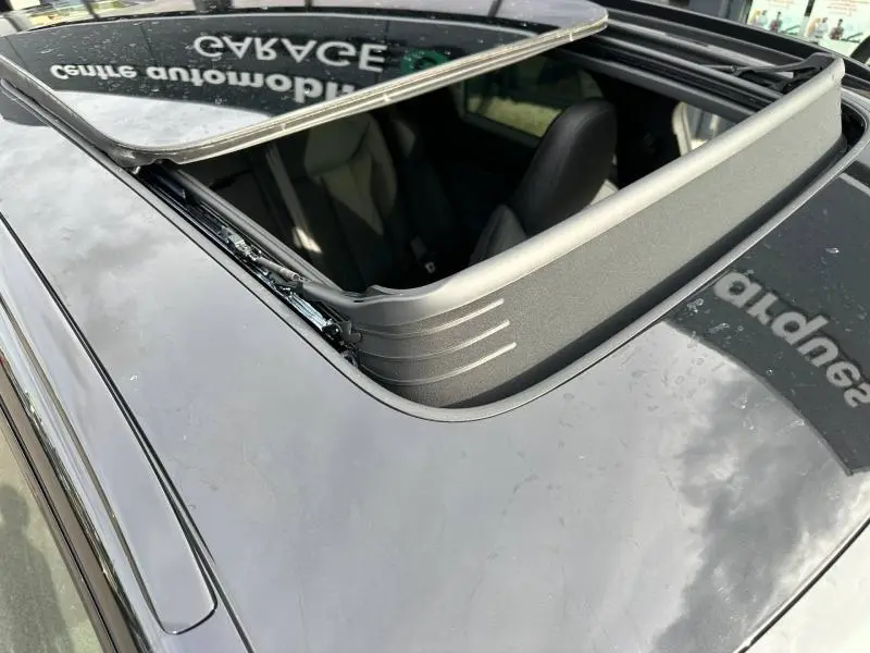 Vue en plongée du toit ouvrant ouvert sur l'Audi Q3 noir Mythique métallisé, avec intérieur cuir visible.