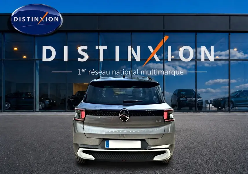 Vue arrière du Citroën C3 Aircross gris mercury 2026, avec feux LED et logo centré sur un parking devant un showroom.