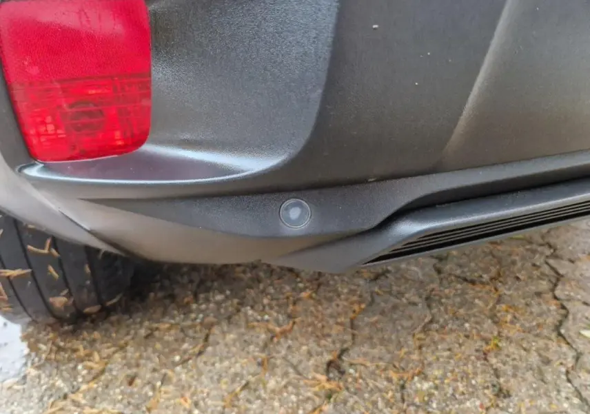 Gros plan sur le pare-chocs arrière noir du Peugeot 3008 2019 avec feu rouge et capteur de stationnement visible.