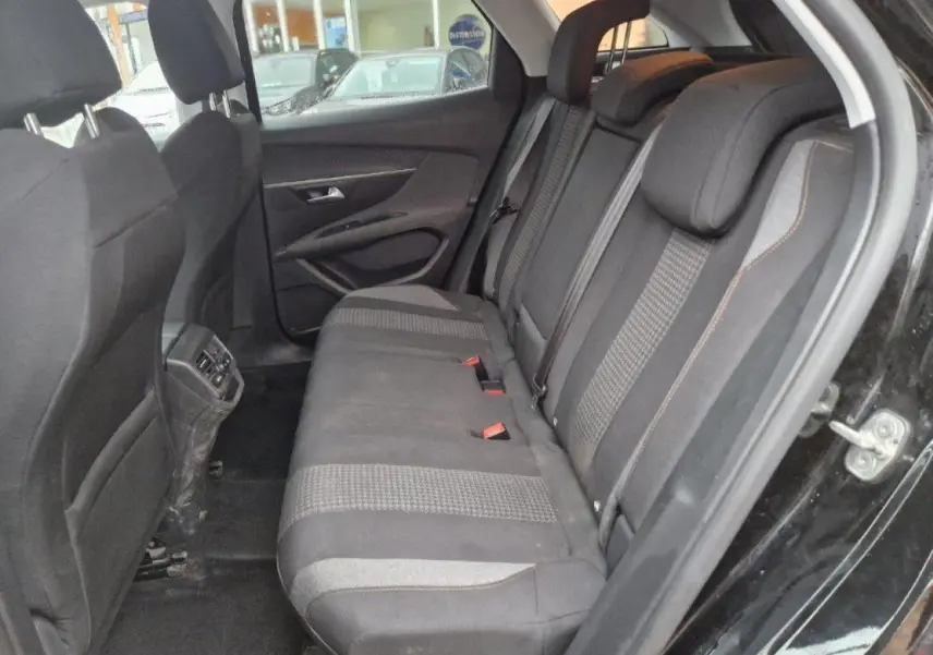 Vue côté droit de l'intérieur arrière d'une Peugeot 3008 noire, montrant les sièges tissu et les aérateurs arrière.
