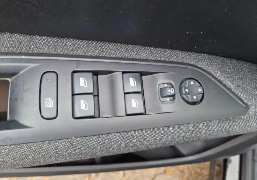 Commandes des vitres électriques et réglage des rétroviseurs sur la portière côté gauche d'un Peugeot 3008 noir 2019.