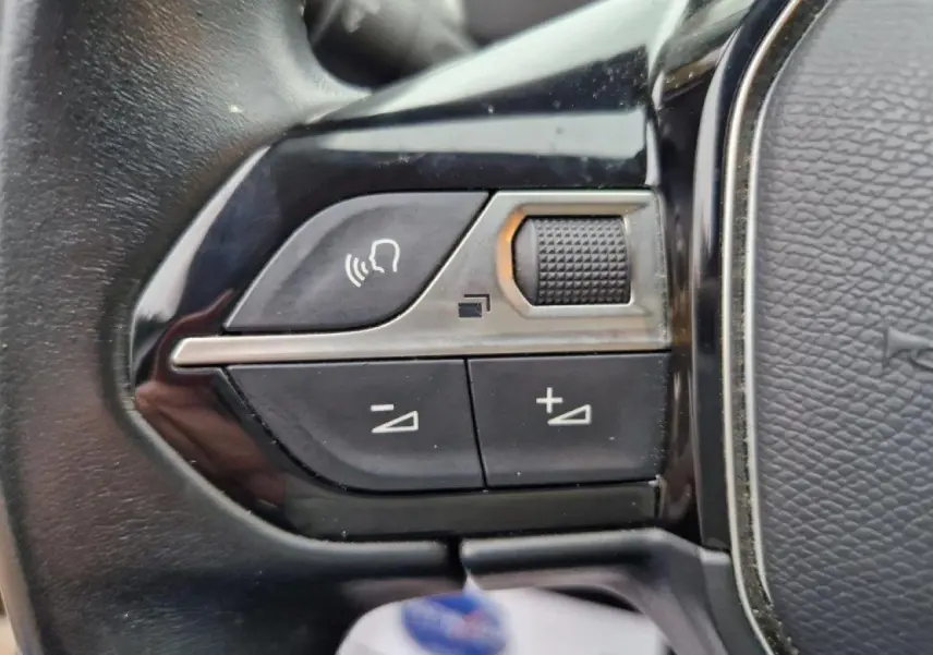 Gros plan sur les commandes vocales et volume du volant cuir noir du Peugeot 3008 noir 2019 côté gauche.
