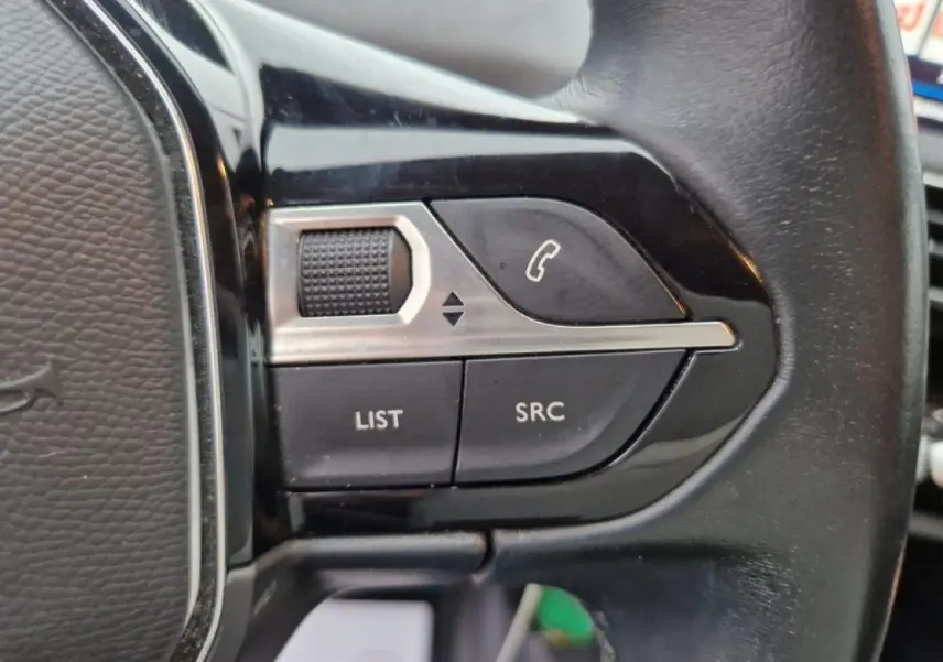 Gros plan sur les commandes gauche du volant cuir noir du Peugeot 3008 2019 avec boutons LIST et SRC visibles.