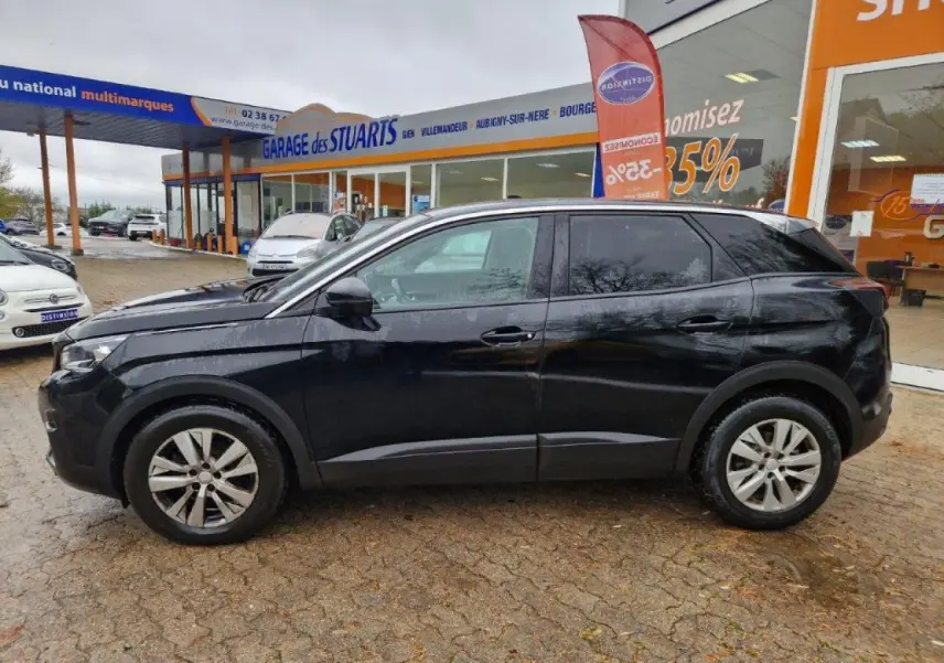 Profil côté gauche d'un Peugeot 3008 noir 2019 garé devant un garage avec jantes alliage 17 pouces.