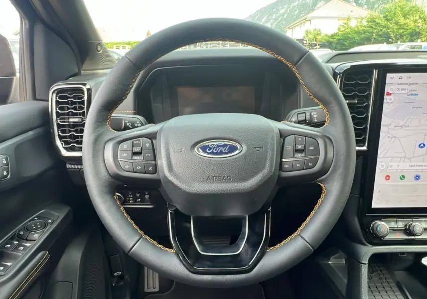 Volant en cuir noir avec surpiqûres marron du Ford Ranger 2.3 PHEV Wildtrak Plus 2025, vue de face sur le tableau de bord et écran tactile.