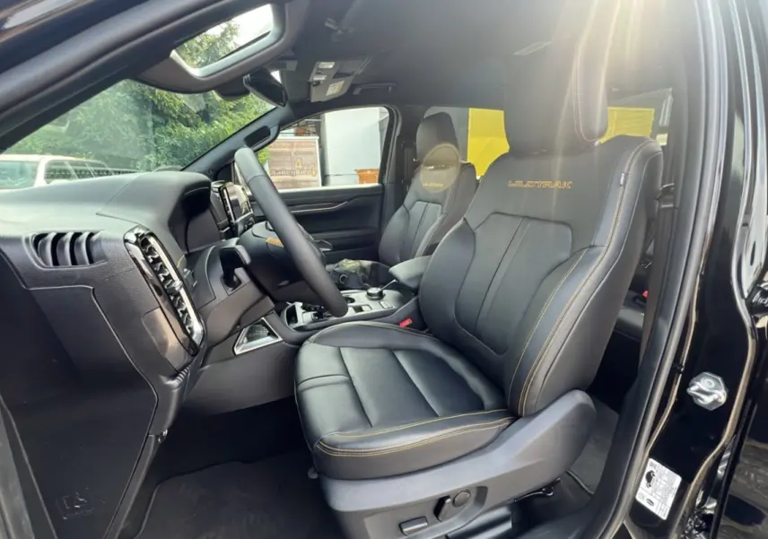 Intérieur côté conducteur du Ford Ranger 2025 noir agate, sièges Wildtrak en cuir noir avec surpiqûres jaunes visibles.