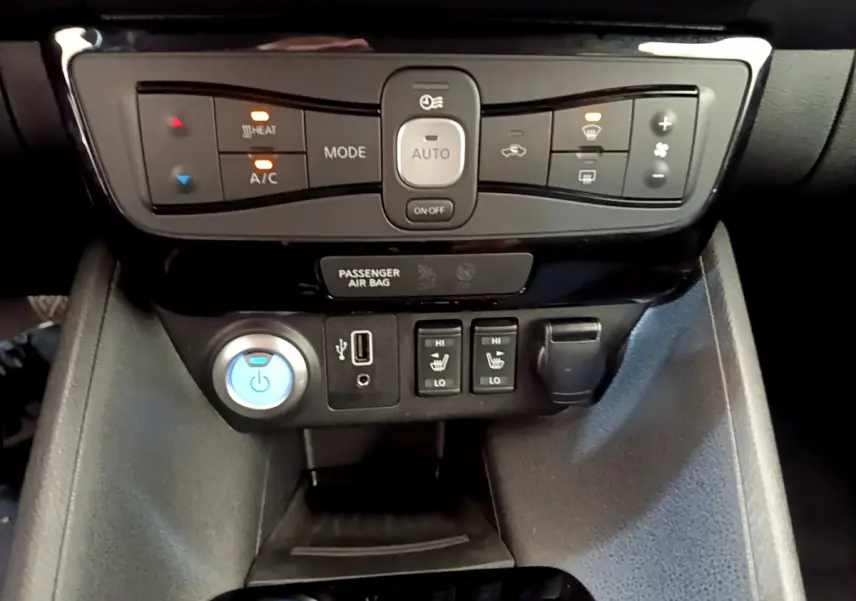 Vue rapprochée du tableau de bord central de la Nissan Leaf 62 kWh blanc, montrant commandes climatisation et sièges chauffants.