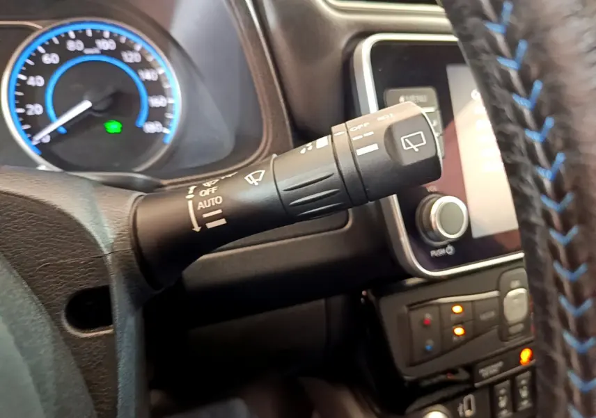 Gros plan sur la commande d'essuie-glace à gauche du volant cuir bleu sur tableau de bord Nissan Leaf blanc 2020.