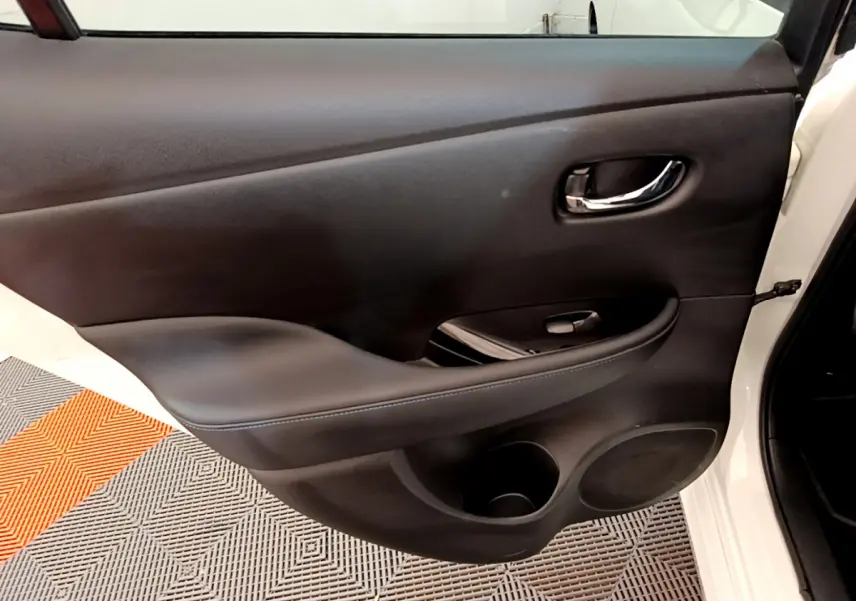 Gros plan sur la porte intérieure côté gauche blanche du Nissan LEAF 62 kWh Business+ avec accoudoir et poignée chrome.