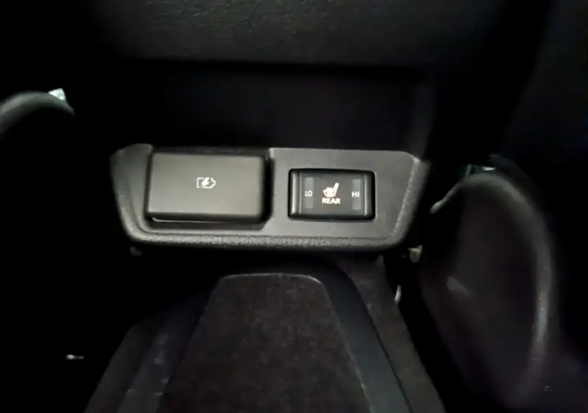 Gros plan sur les commandes de chauffage des sièges arrière et prise électrique dans l'habitacle noir d'une Nissan Leaf blanche.