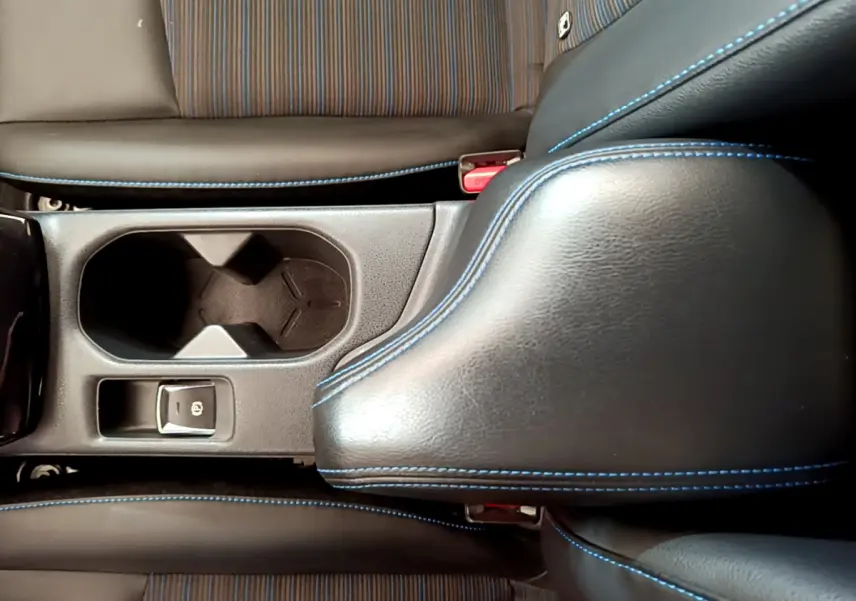 Gros plan sur la console centrale noire avec surpiqûres bleues et porte-gobelet du Nissan Leaf blanc 2020.