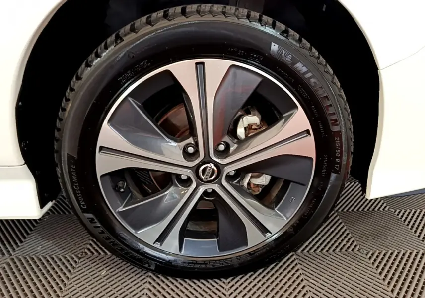 Gros plan sur la jante alliage bicolore et pneu Michelin d'une Nissan Leaf blanche côté avant droit.