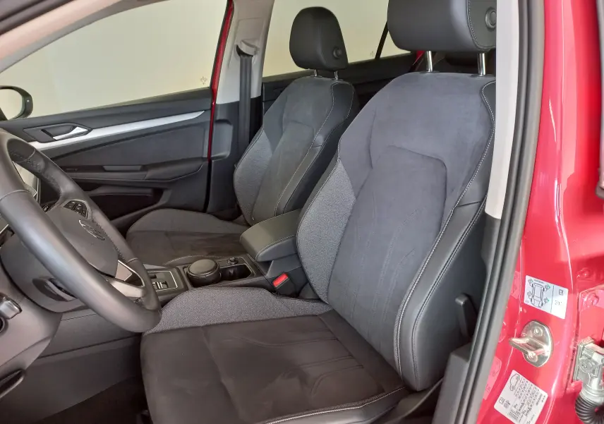 Vue intérieure côté conducteur de la Volkswagen Golf Rouge Roi 2024, sièges avant en tissu et cuir gris foncé.