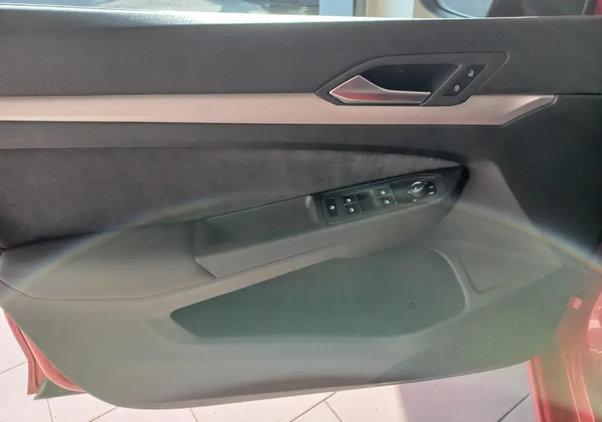 Vue intérieure de la porte avant gauche d'une Volkswagen Golf Rouge Roi, avec commandes de vitres et verrouillage.