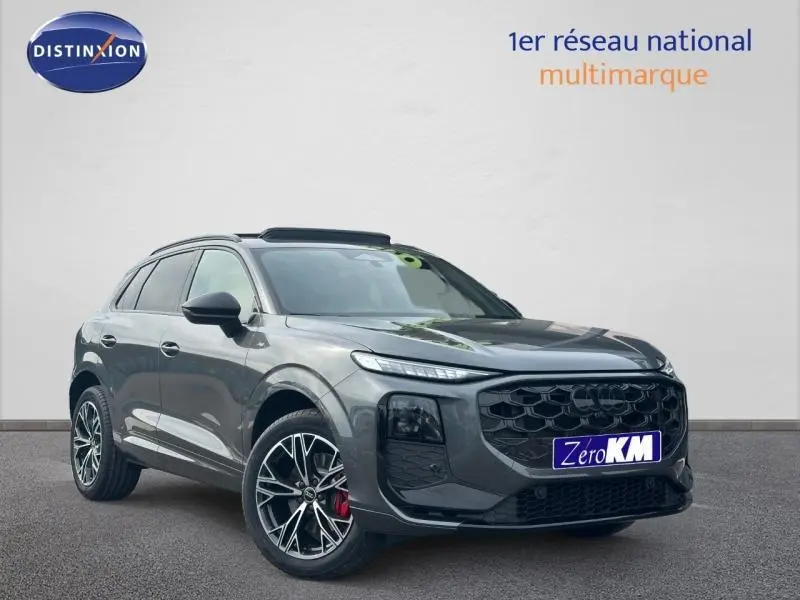 Audi Q3 2.0 TDI gris en 3/4 avant droit, avec calandre noire et jantes alliage noires à détails rouges.