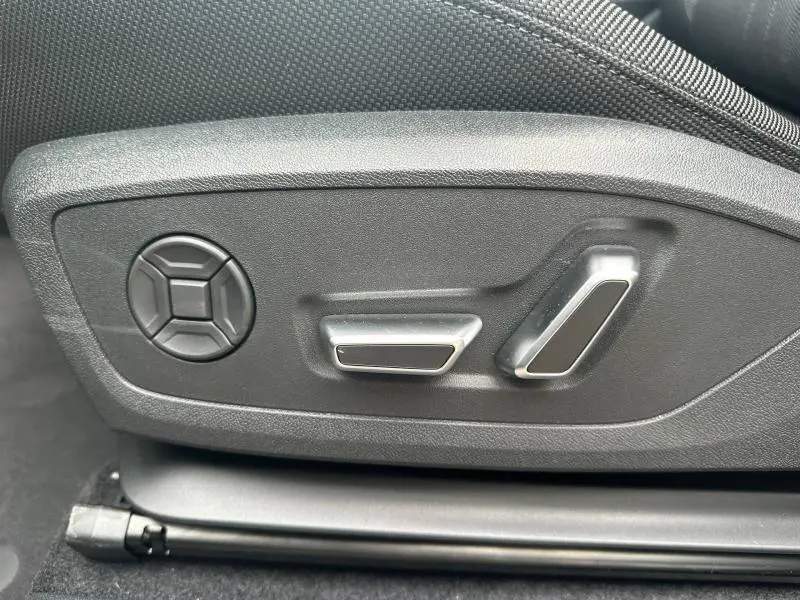 Gros plan sur les commandes électriques de réglage du siège côté gauche d’un Audi Q3 gris 2026 finition S line.
