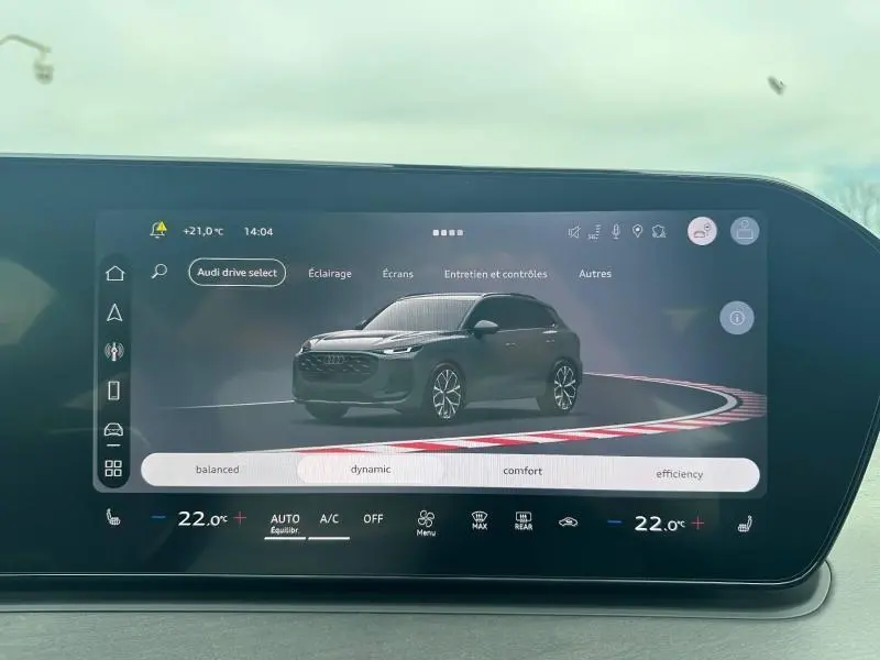 Vue 3/4 avant d’un Audi Q3 gris 2026 affiché sur l’écran tactile du tableau de bord avec options de conduite.