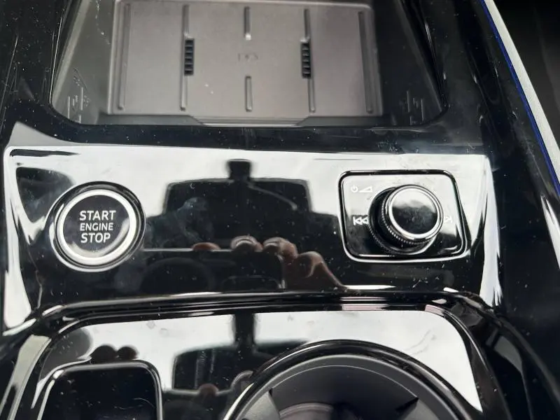 Détail de la console centrale noire brillante de l'Audi Q3 2026 avec bouton Start Engine Stop et molette de contrôle.