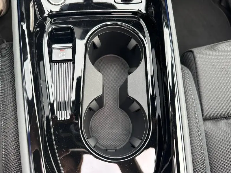 Vue rapprochée de la console centrale noire brillante avec porte-gobelets et frein à main électronique de l'Audi Q3 gris 2026.