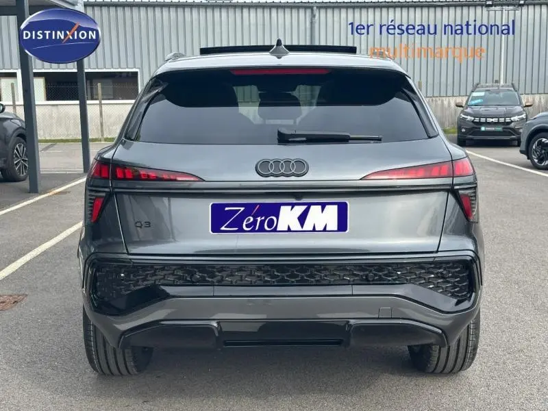 Vue arrière d'un Audi Q3 gris 2026 avec feux LED étirés et logo S line sur un parking extérieur.