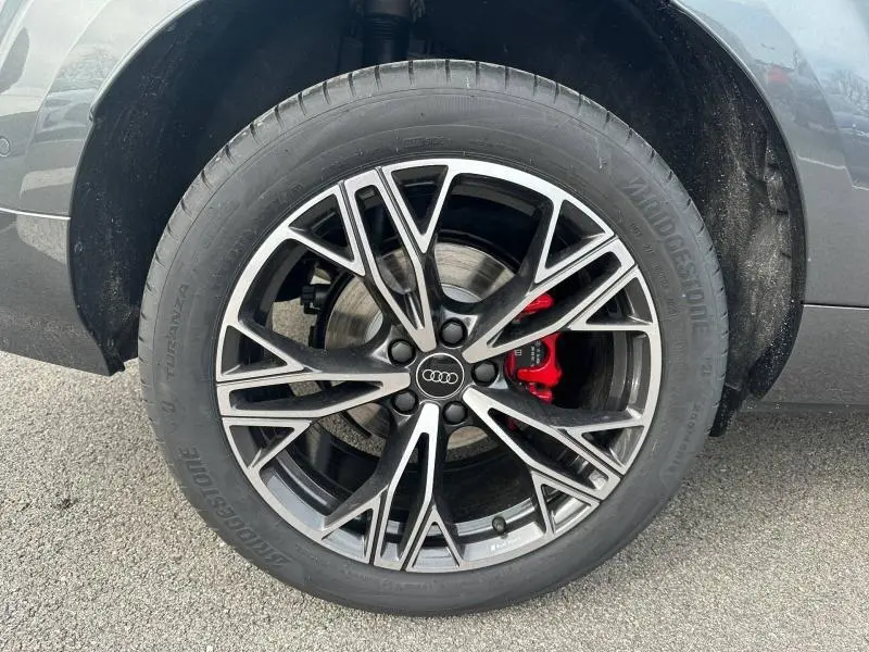 Gros plan sur la roue avant droite d’un Audi Q3 gris 2026, jante alliage noire et argent avec étrier de frein rouge.