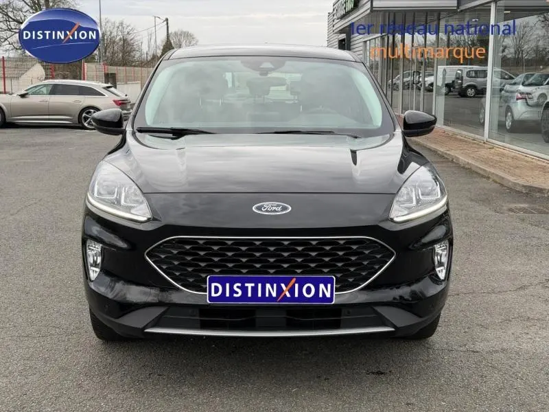Vue frontale d'un Ford Kuga 1.5 EcoBoost 150ch Titanium 2024 noir, avec calandre hexagonale et phares LED allumés.
